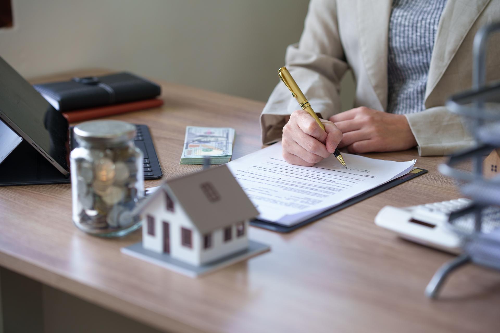 female real estate agent offers home equity loans to clients with loan calculations and home sales contracts in the office. Real estate and insurance buying savings concept