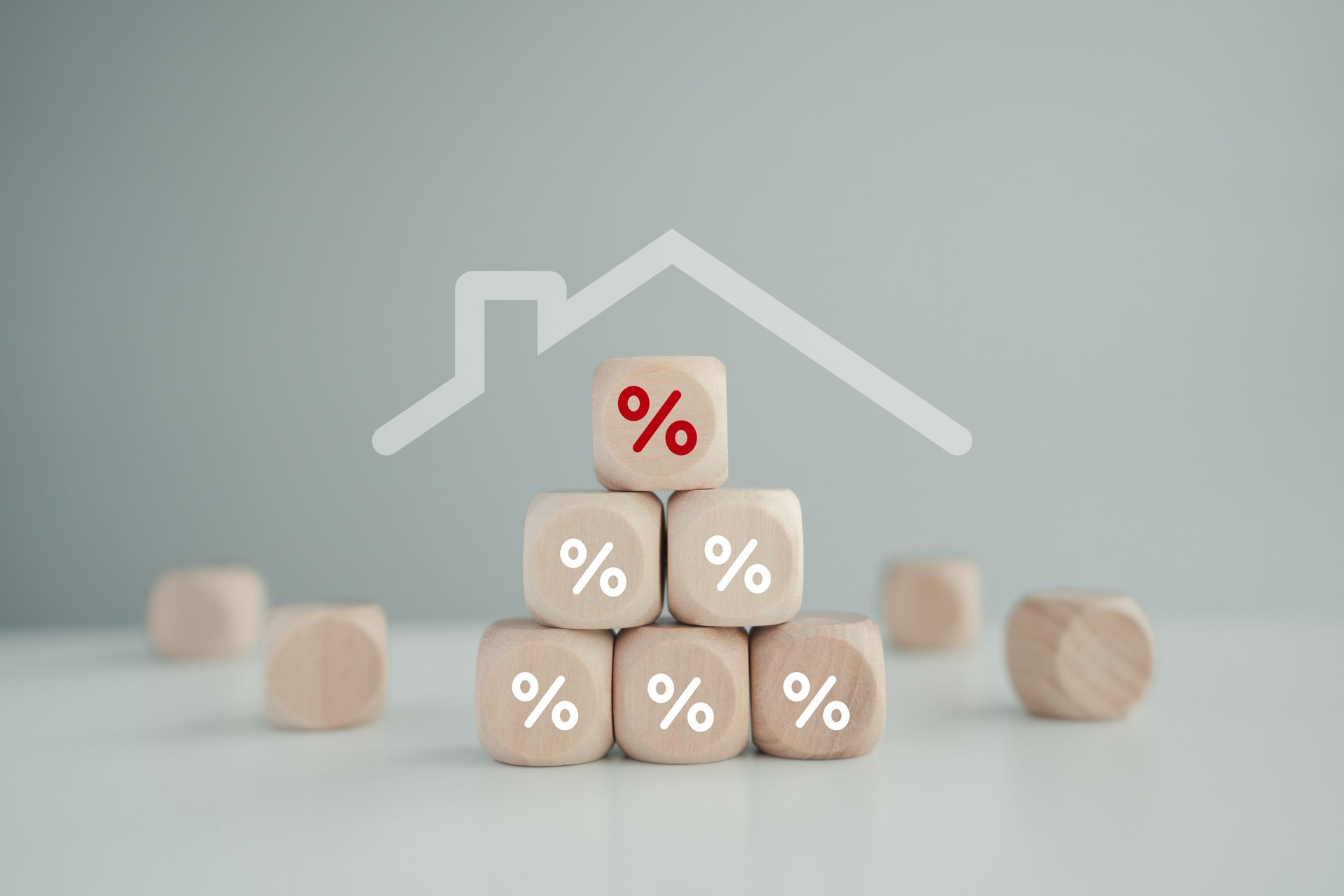 Percentage sign on stack of wooden block with roof house. Reduce the interest rates of home loan, Housing finance concept.